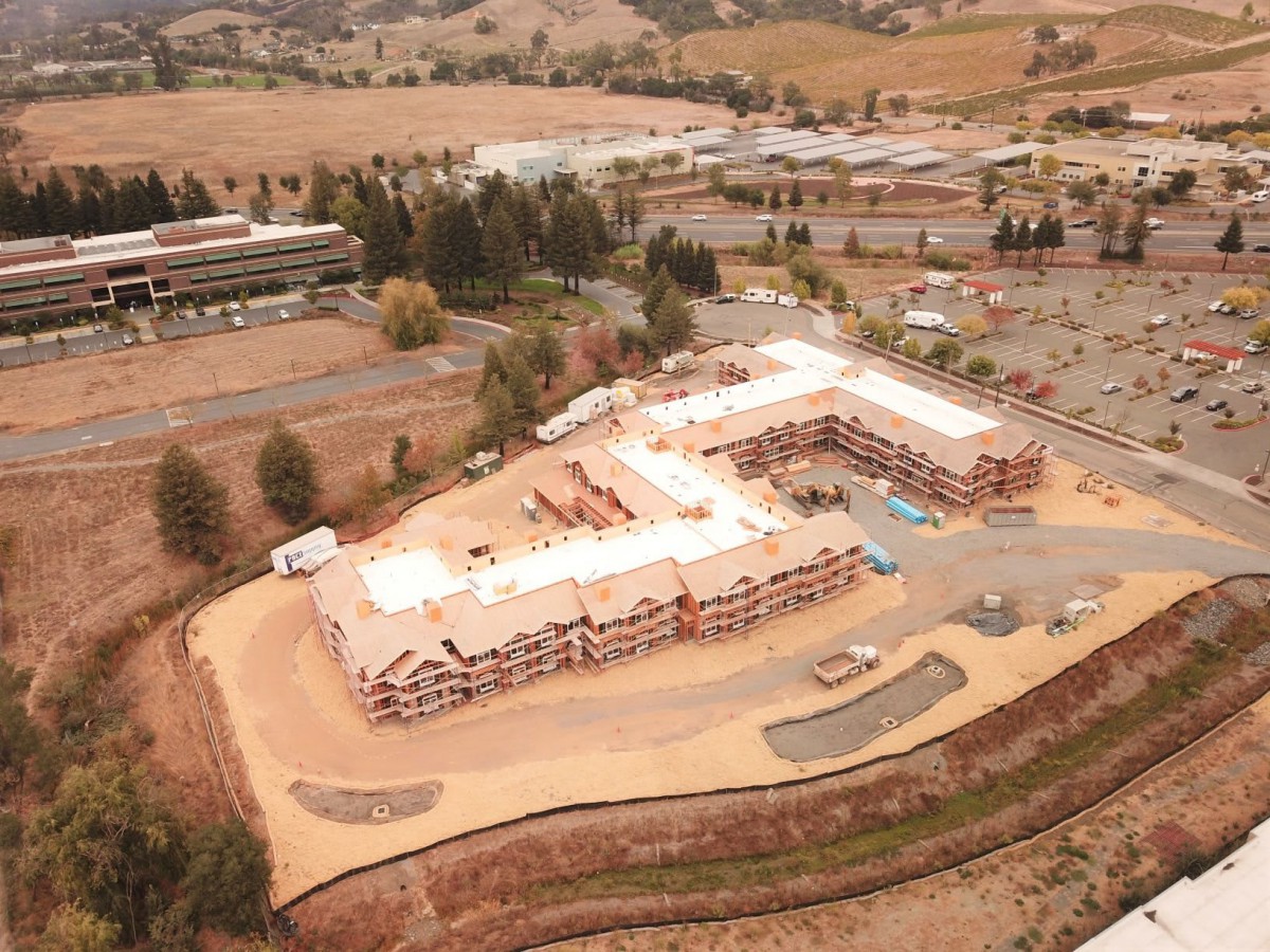 Aerial view of a construction site with an L-shaped building under development surrounded by hills.