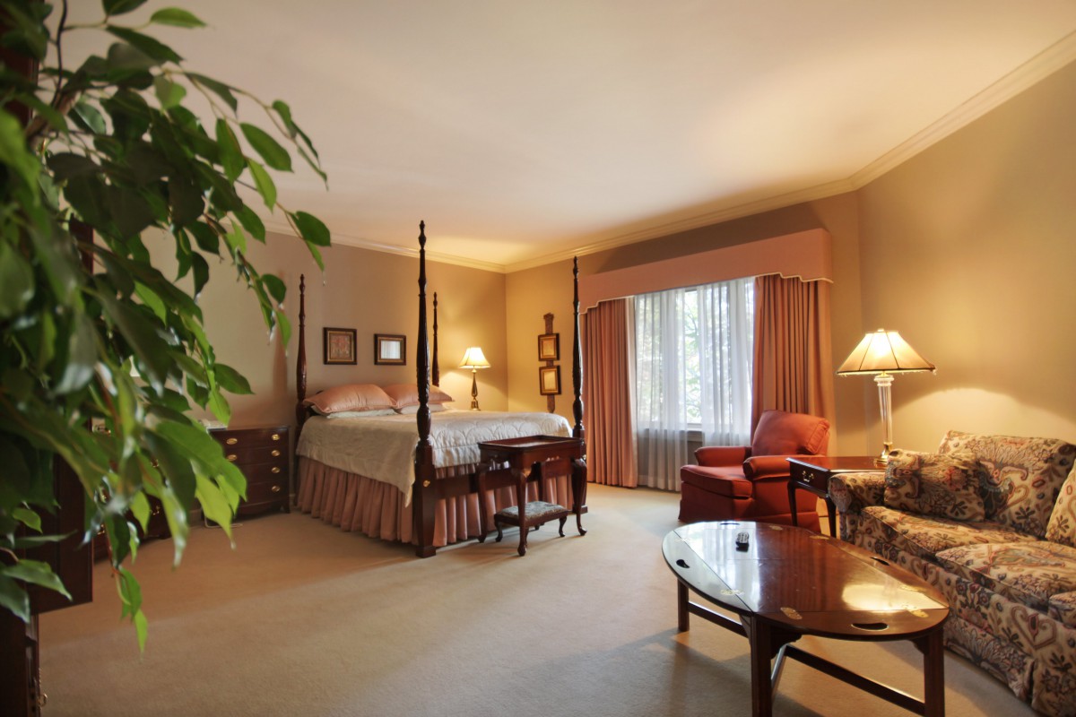A cozy and well-decorated bedroom featuring a four-poster bed, elegant curtains, and warm lighting.