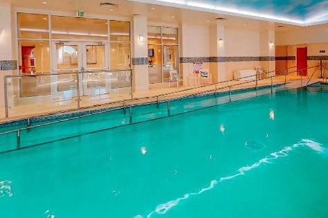 An inviting indoor swimming pool with clear water and safety railings.
