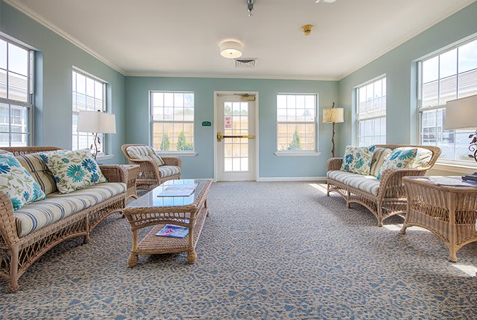 A bright and modern living room with wicker furniture and large windows.