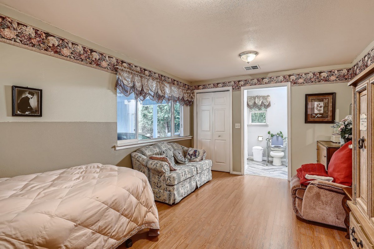 A cozy bedroom with a bed, couch, and wooden flooring.