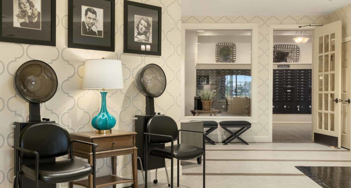 A vintage-style hair salon interior featuring art deco elements, framed photographs, and classic furniture.