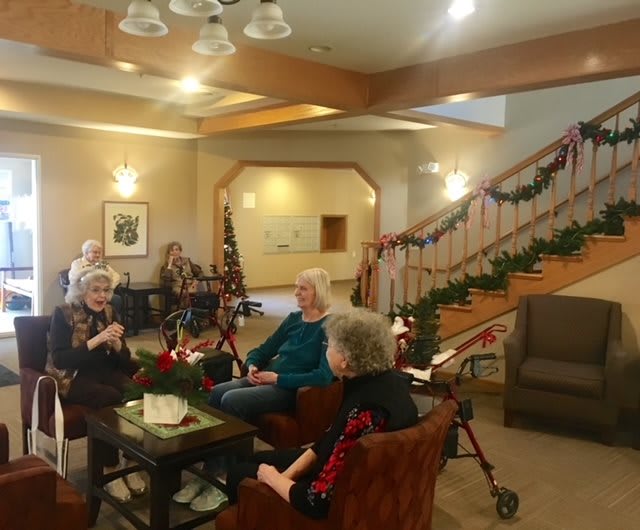 A cozy lounge area with elderly individuals engaged in conversation, adorned with holiday decorations.