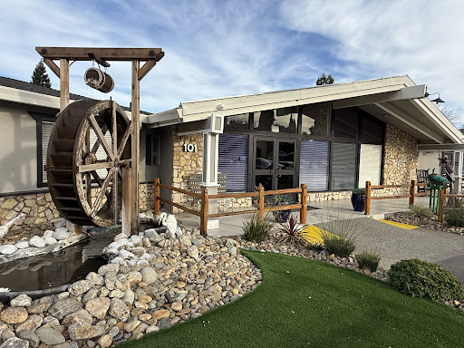 A charming building featuring a traditional water wheel and beautifully landscaped surroundings.