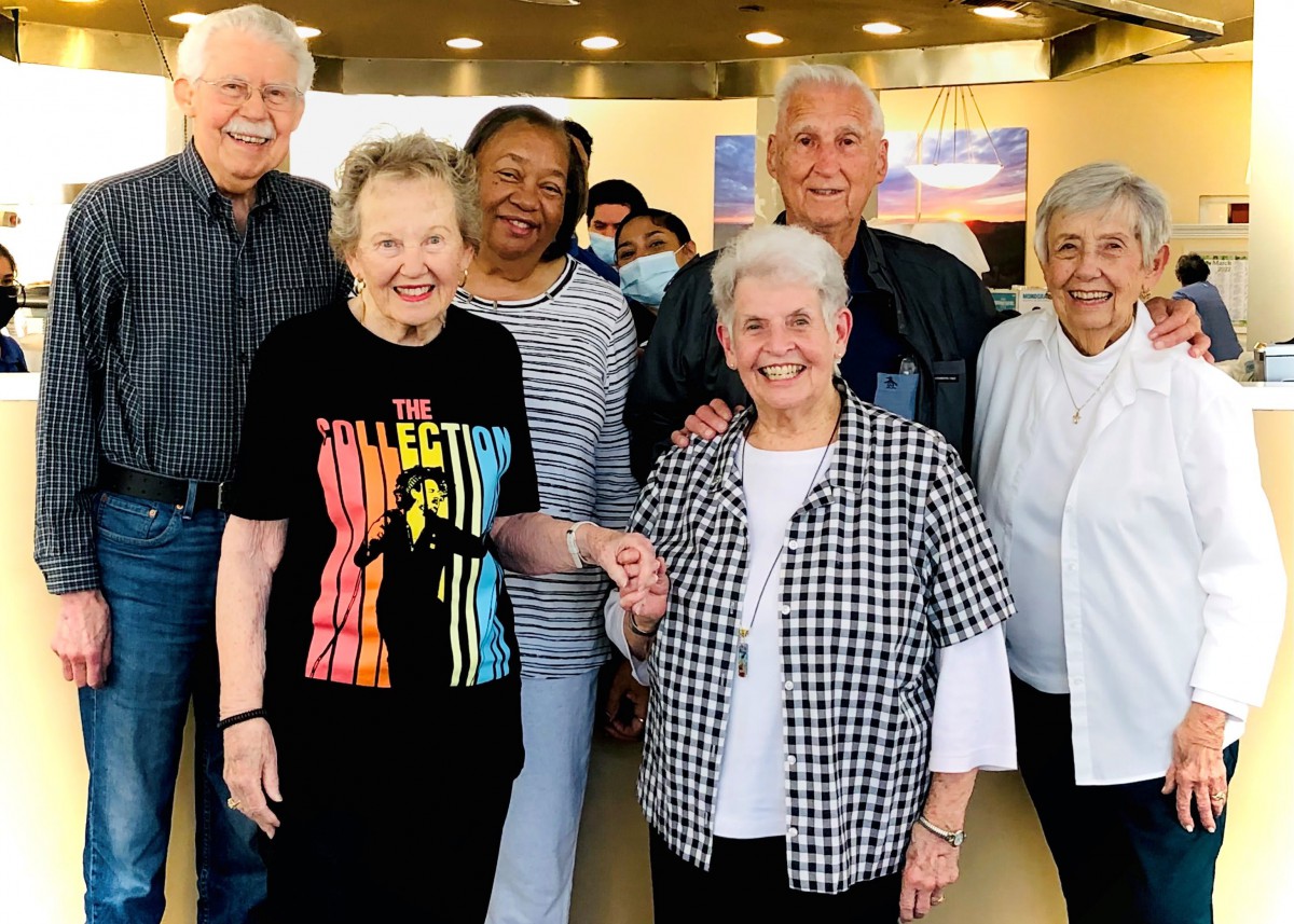 A group of smiling seniors poses together indoors.