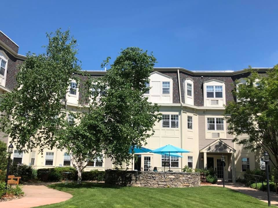 A residential building with a well-maintained lawn and trees on a sunny day.