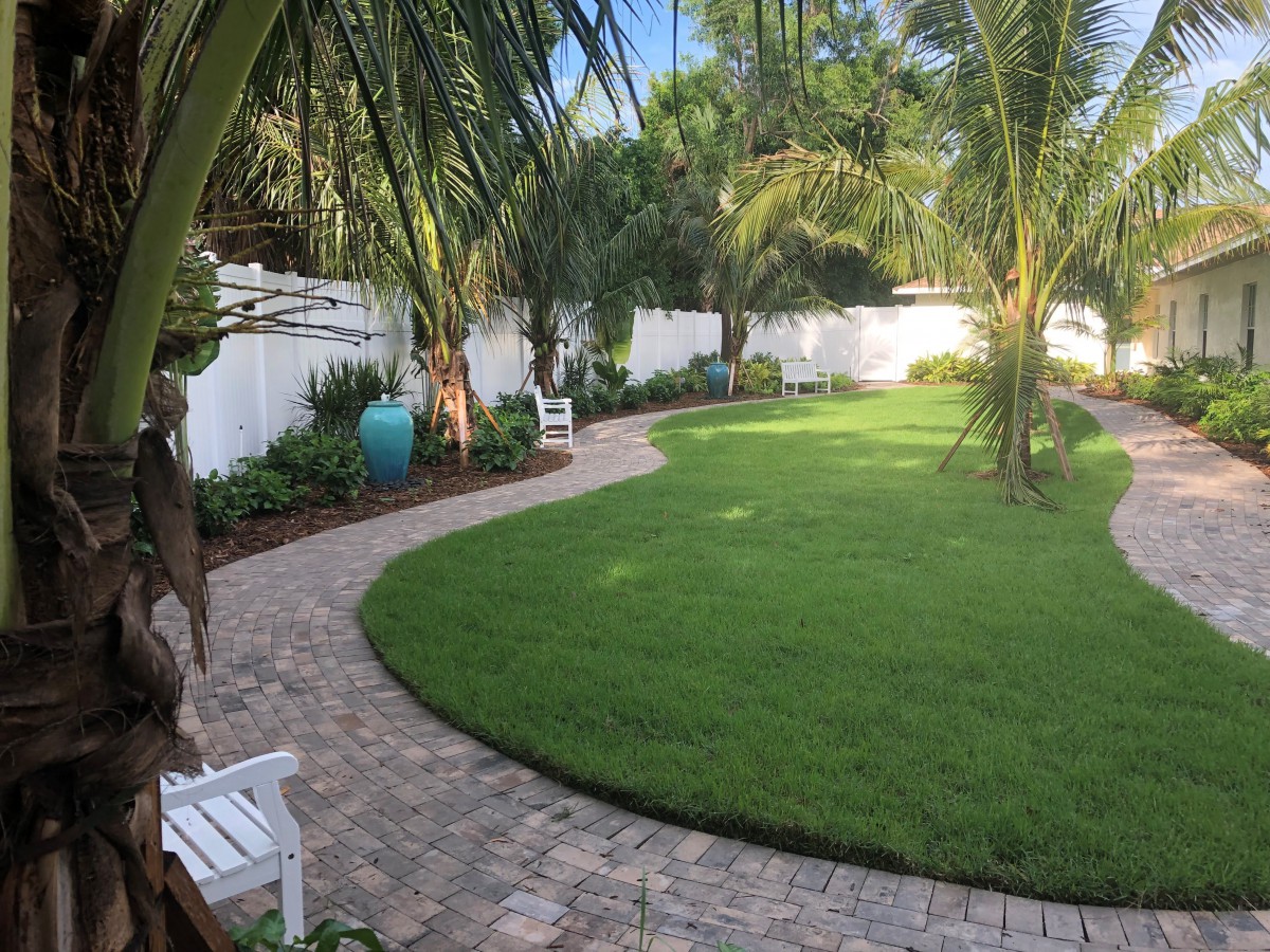 A tranquil garden with a curved brick pathway and lush greenery.
