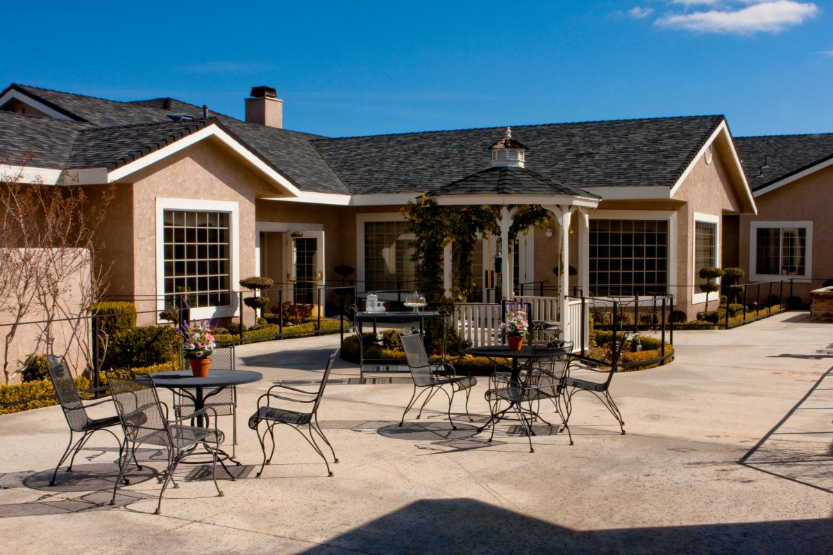 A spacious patio with outdoor furniture in front of a house on a sunny day.