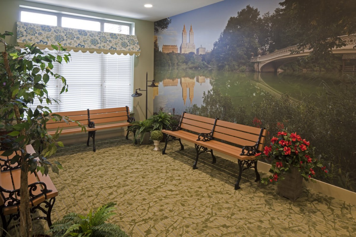 An indoor waiting area with benches and a mural depicting a park-like scene.