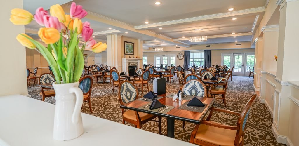 A spacious and elegantly decorated dining area with neatly arranged tables and chairs, featuring floral decorations.