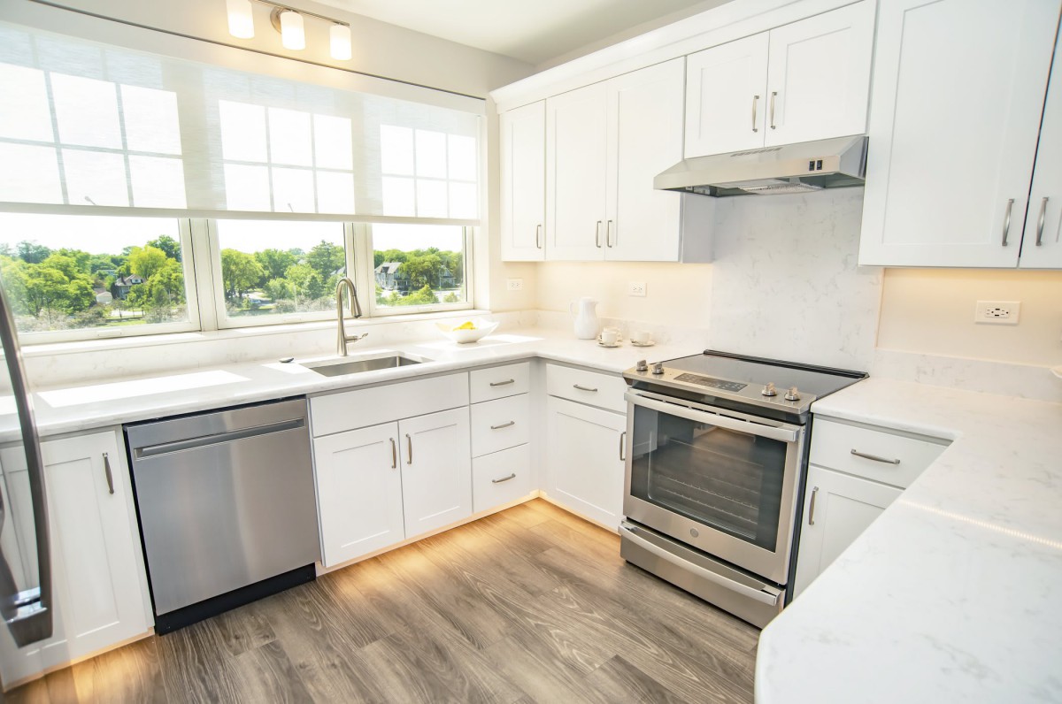 A bright, modern kitchen with white cabinets and stainless steel appliances.