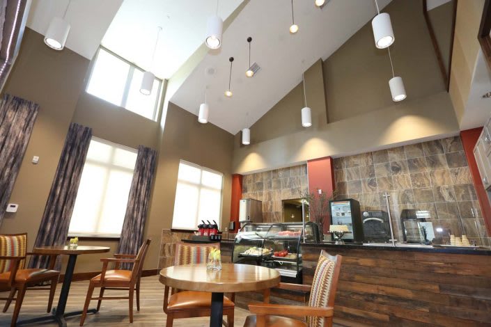 A modern cafe interior with seating and a beverage station.