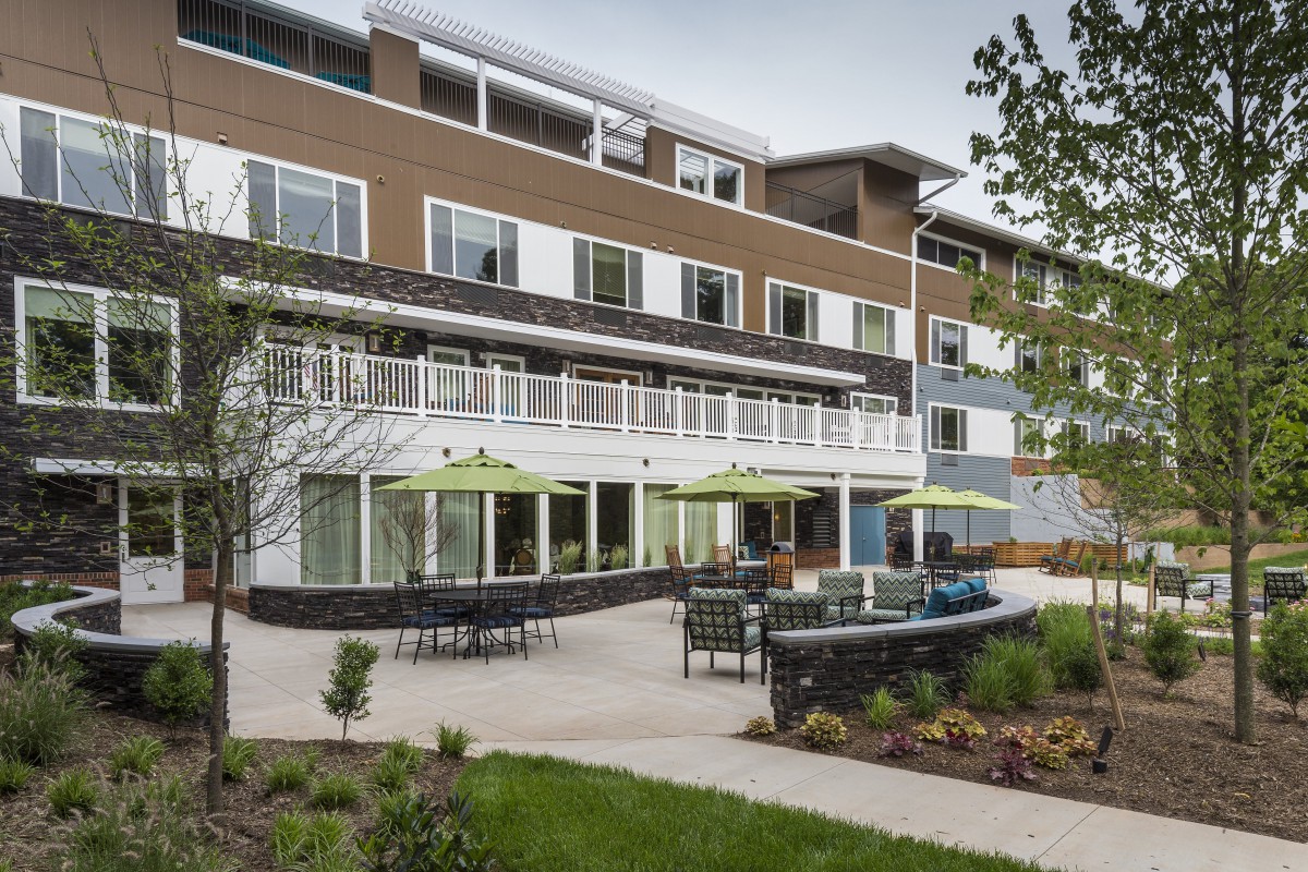 A modern apartment complex with a landscaped patio area and outdoor seating.