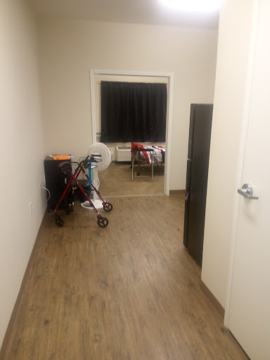 A view of a hallway leading to a room, featuring a stroller and a door.