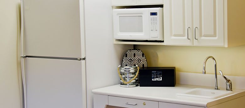 A kitchen area featuring a microwave, decorative items, and a refrigerator.