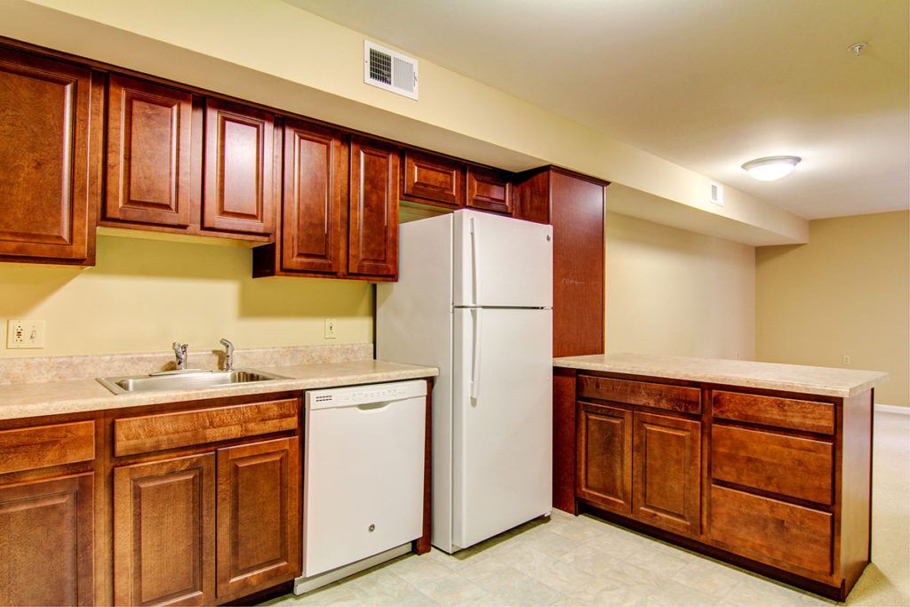 A kitchen with wooden cabinets, a white refrigerator, and a dishwasher.