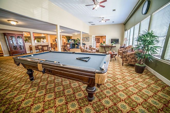 A spacious recreation room featuring a billiards table and comfortable seating.