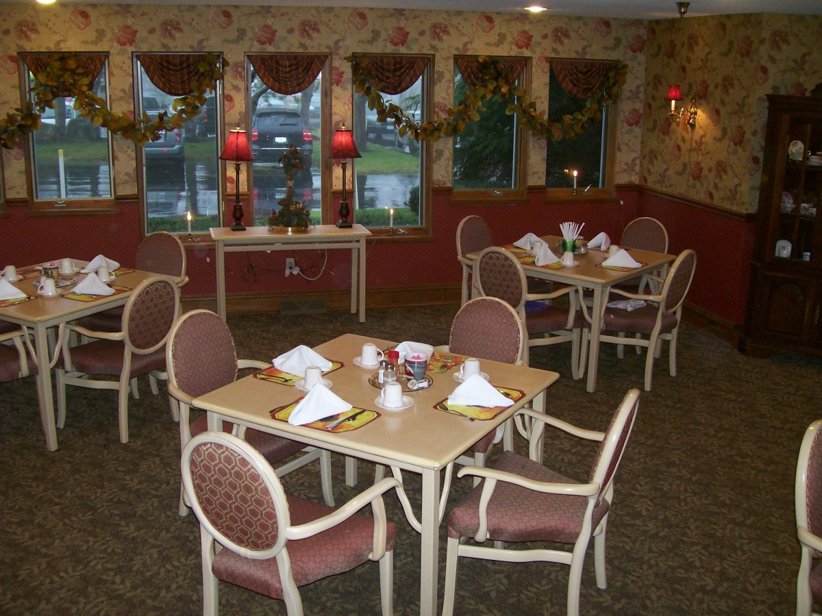 A cozy dining room setup with neatly arranged tables and chairs, decorated for a welcoming ambiance.