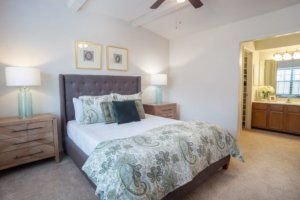 A cozy and well-decorated bedroom with a neatly made bed, accent pillows, and a stylish lamp.