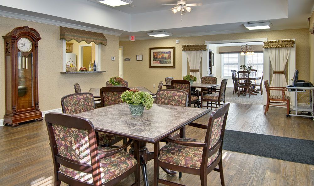 A cozy dining area with several tables and chairs, decorated with potted plants.