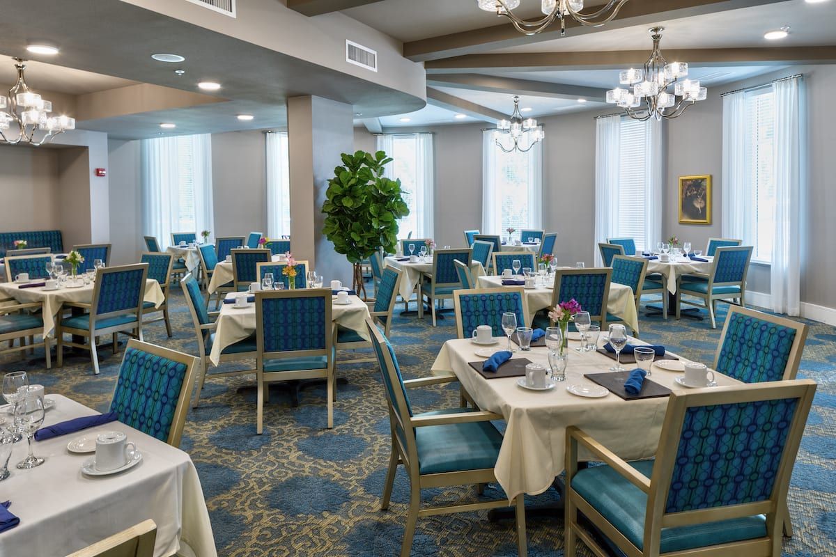 A well-appointed dining room with elegantly set tables and chandeliers.