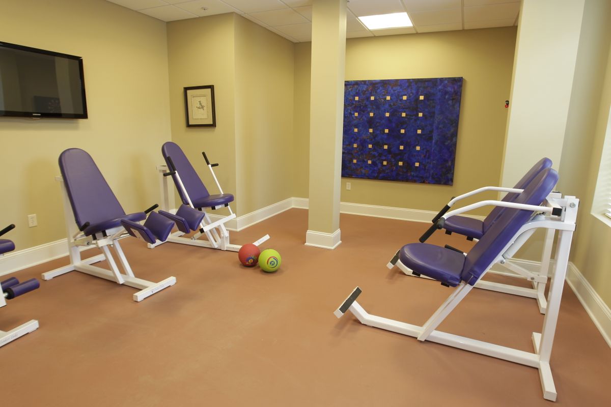 A small gym with workout machines and medicine balls.