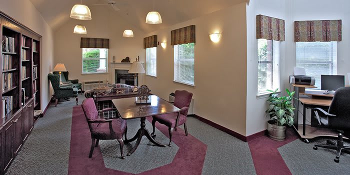 A cozy dining room with a table and chairs, featuring large windows and warm lighting.