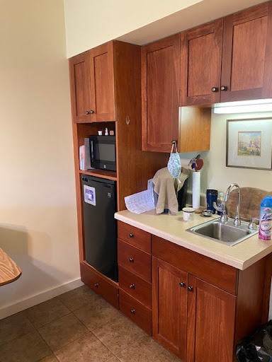 A compact kitchenette featuring wooden cabinets, a sink, microwave, and refrigerator.