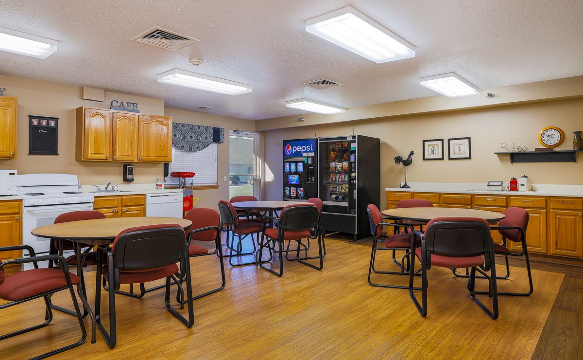 A spacious break room with tables, chairs, and a vending machine.