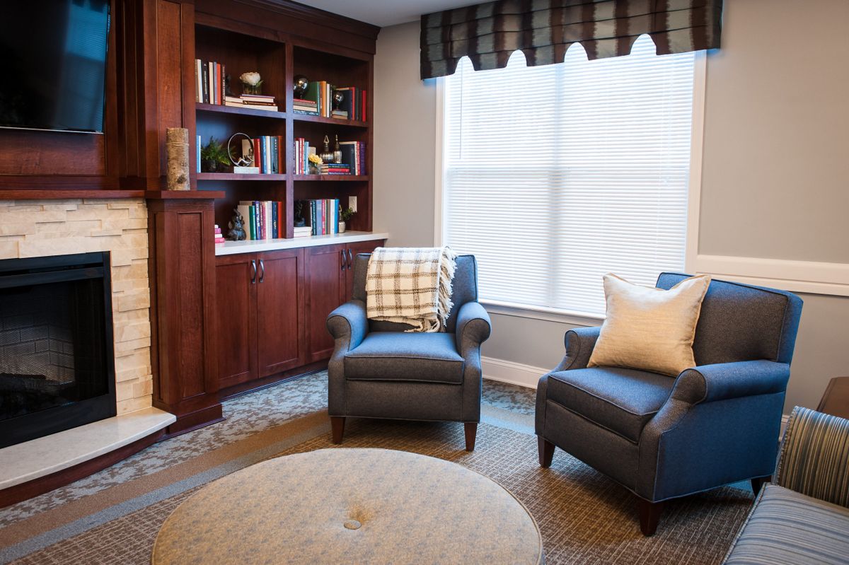 A cozy living room with two armchairs, a bookshelf, and a large window.