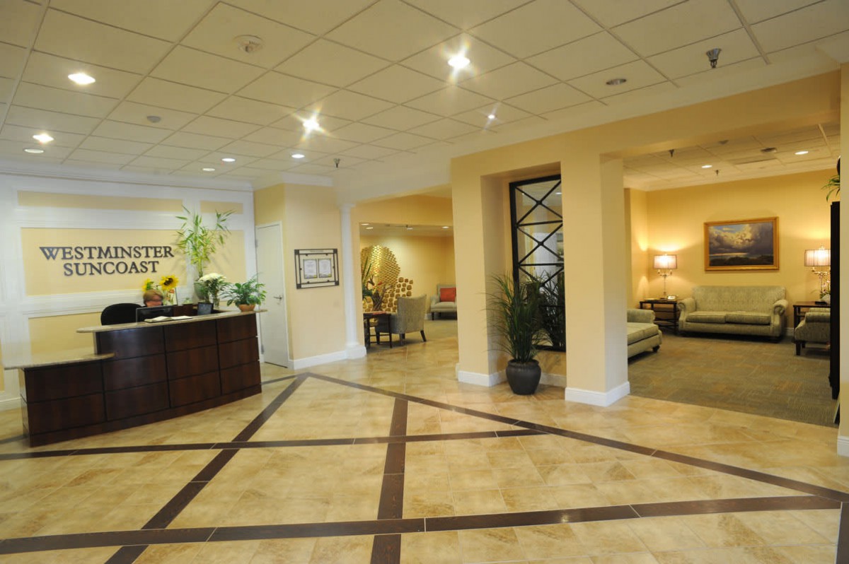 A spacious hotel lobby with a reception desk, elegant furniture, and decorative plants.