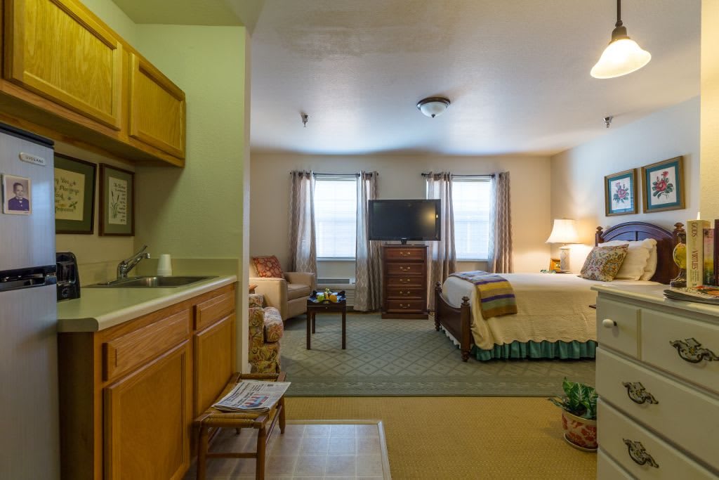A cozy studio apartment featuring a sleeping area, kitchenette, and living space.
