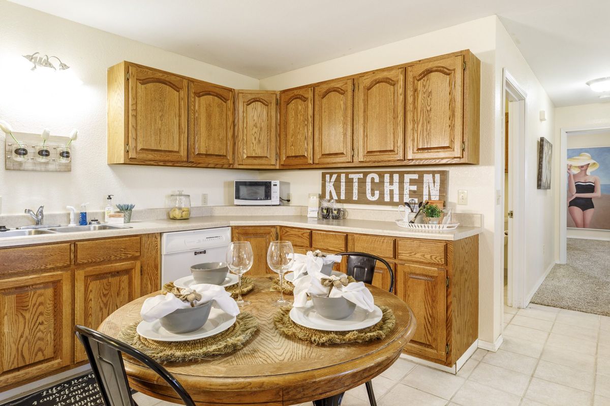A cozy kitchen with wooden cabinets and a set dining table, showcasing rustic decor elements.
