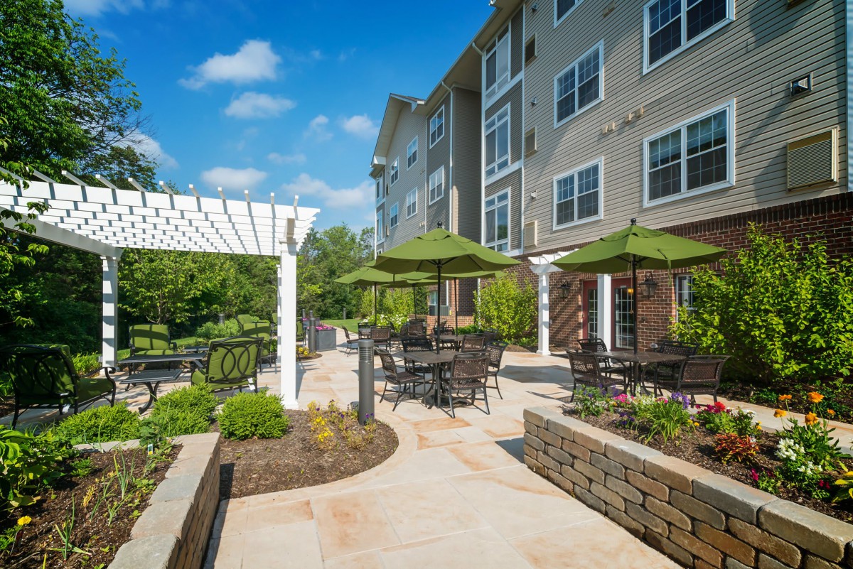 A landscaped patio area with tables and chairs outside an apartment building.