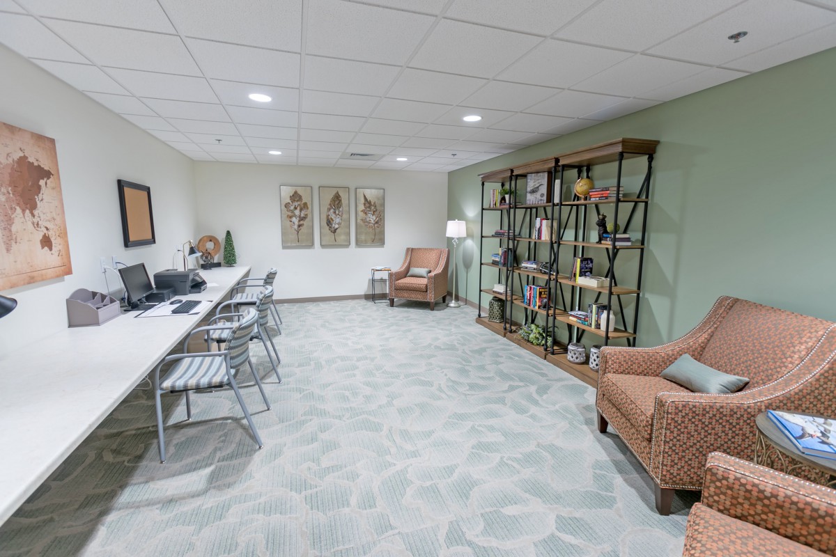 A modern office space featuring workstations with computers, a comfortable seating area, and bookshelves for storage and display.