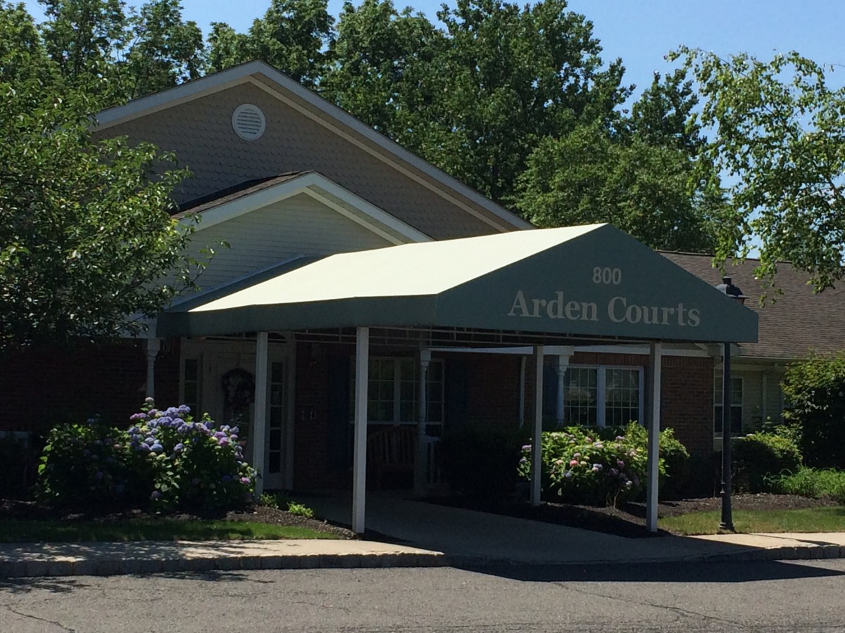 An outdoor view of a building entrance with an awning and surrounding greenery.