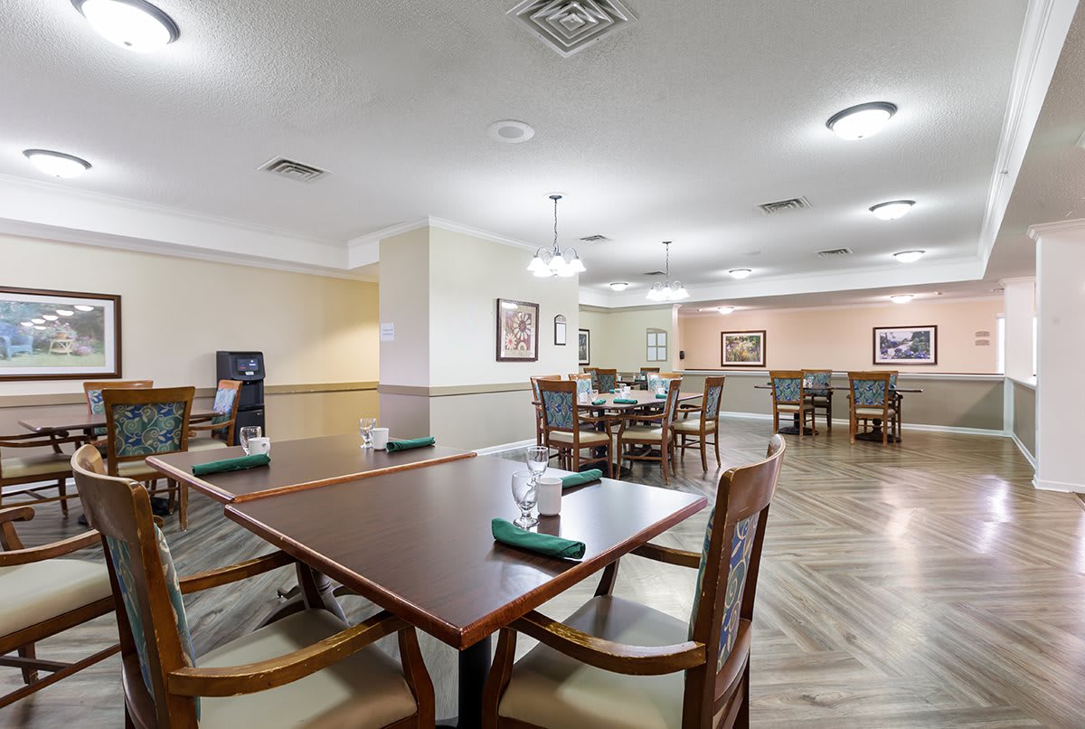 A spacious dining area with neatly arranged tables and chairs, featuring elegant lighting and wooden furnishings.