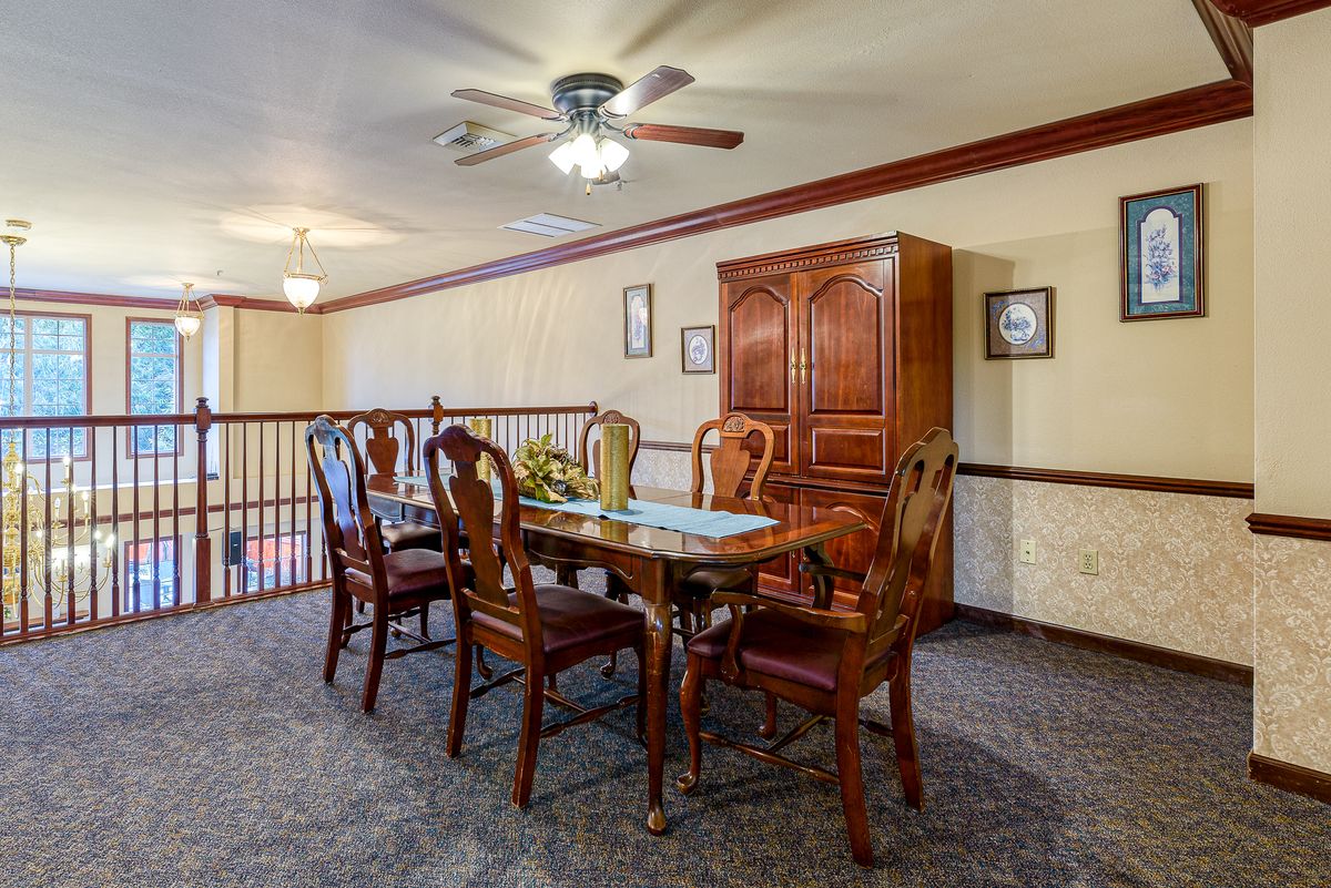A dining area featuring a wooden table with chairs, a cabinet, and a ceiling fan.