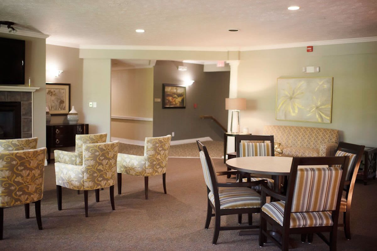 A cozy living room with multiple seating areas, featuring tables and a warm ambiance.