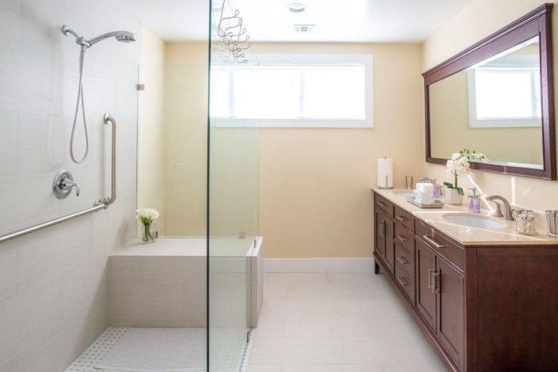 A modern and clean bathroom with a glass shower, double vanity, and large mirror.