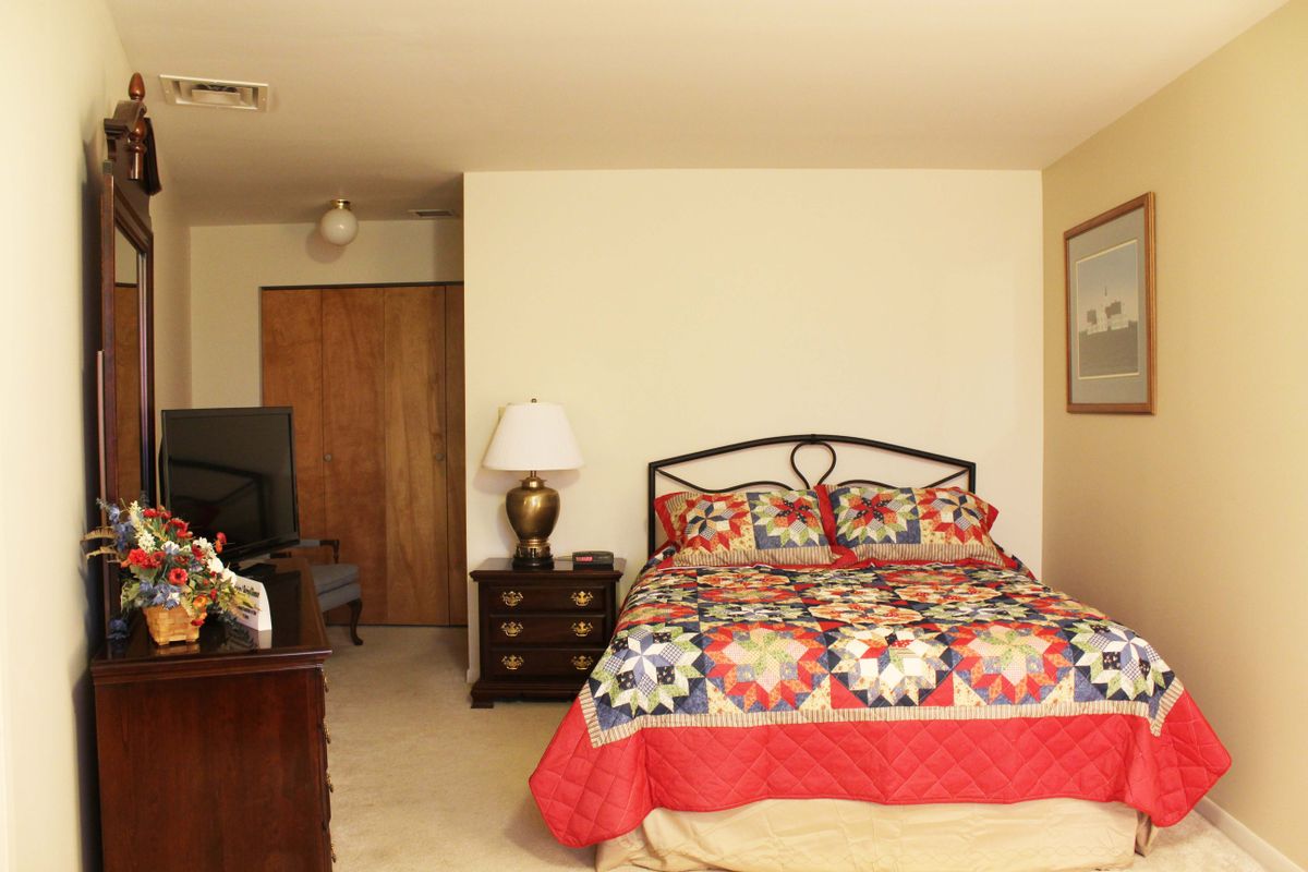 A cozy bedroom with a colorful quilt and classic wooden furniture.