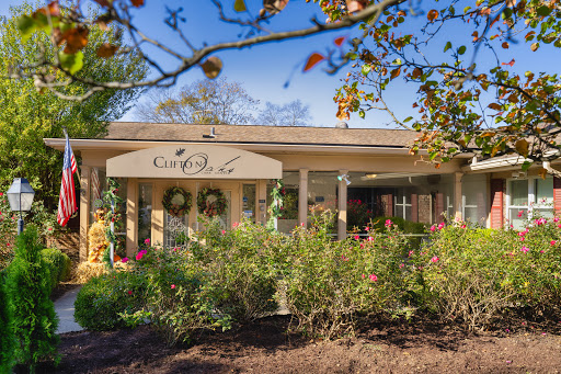 A charming home with a welcoming porch surrounded by blooming flowers and lush greenery.