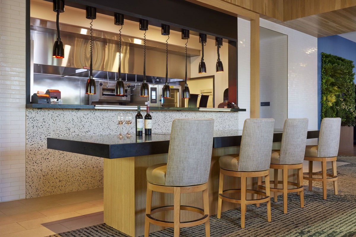 A modern bar area with high chairs and wine bottles.