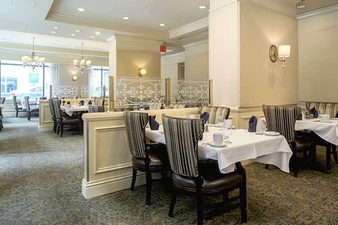 An elegantly set dining area in a restaurant with neatly arranged tables and chairs.