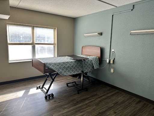A clean and simple hospital room featuring a adjustable bed and a window.
