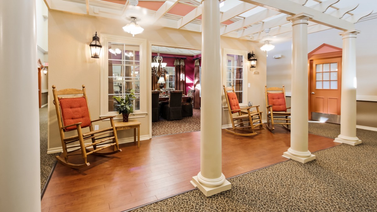 A cozy lobby with rocking chairs and warm lighting, featuring traditional design elements.