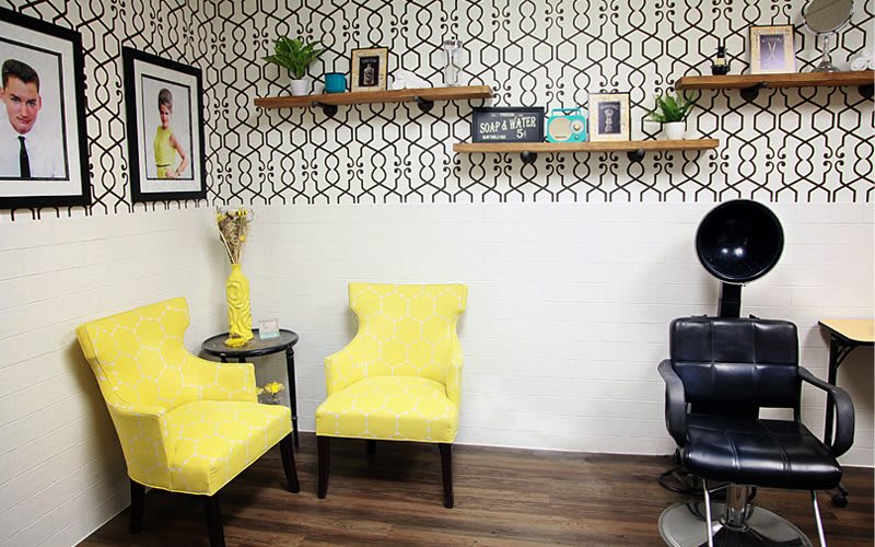 A modern living room with vibrant yellow chairs and stylish shelving against a patterned wall.