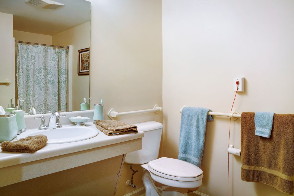 A clean bathroom featuring a sink, toilet, and shower area, with towels neatly hung.
