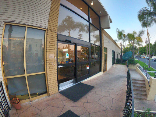A modern storefront with large glass doors and a welcoming entrance, surrounded by palm trees.