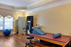 A well-equipped physical therapy room with exercise tools and a treatment table.